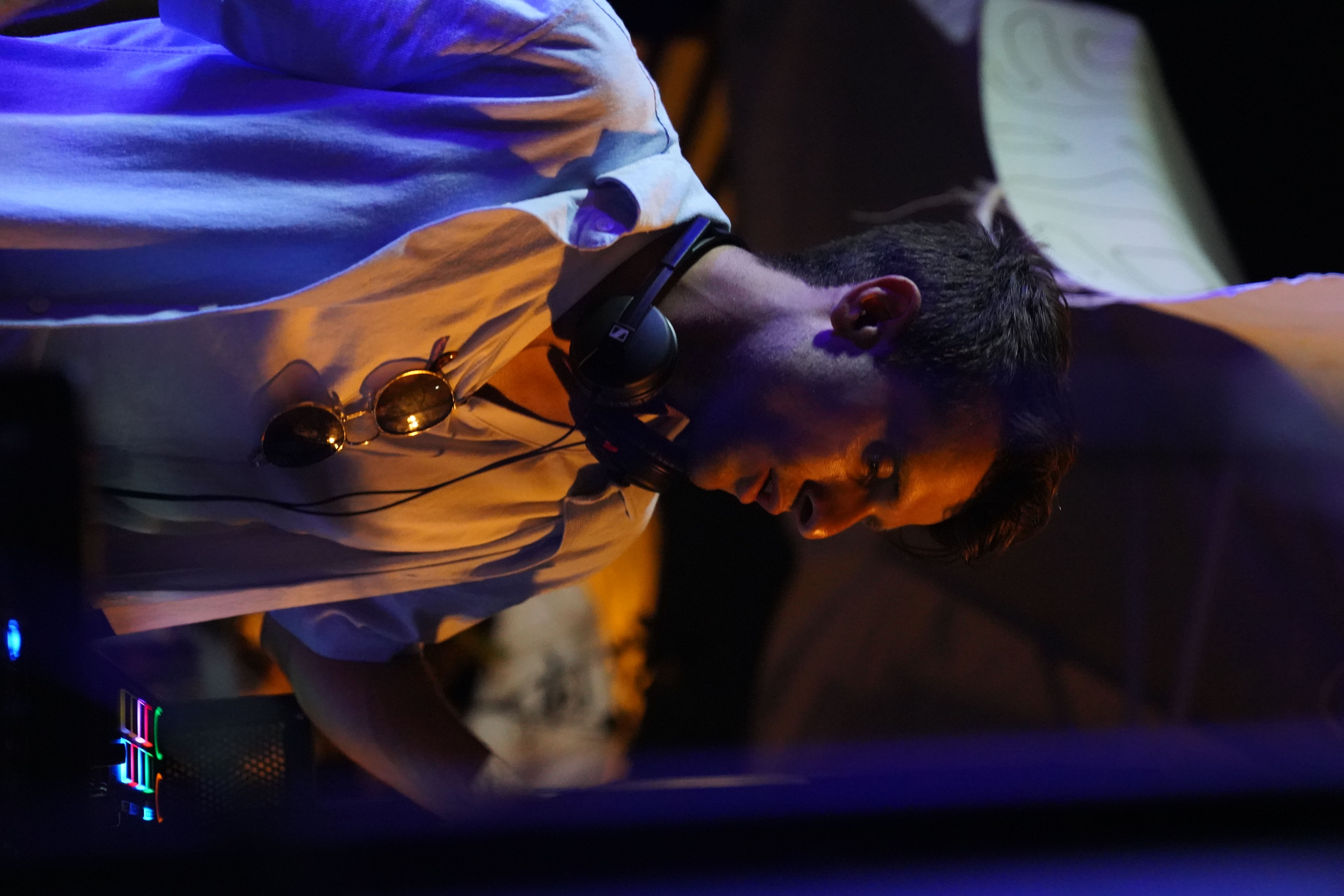 Portrait of Phyles DJing under blue and amber club lighting